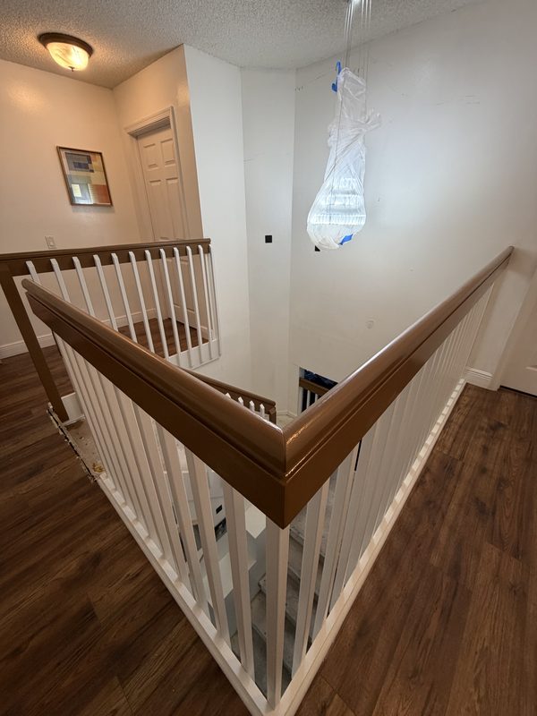 Wooden handrail refinished in warm walnut over white balusters