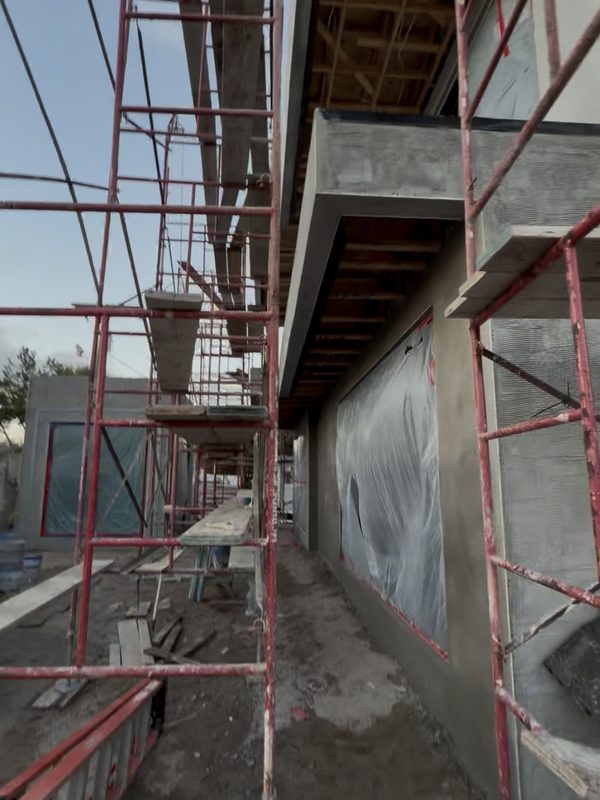 Exterior elevation with scaffolding and masked openings before painting
